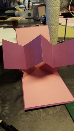 an origami sculpture made out of pink and purple paper on top of a table