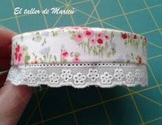 a hand holding a piece of fabric with flowers on it and white trim around the edge