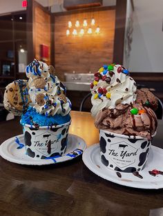 two ice cream sundaes with chocolate frosting and sprinkles on them