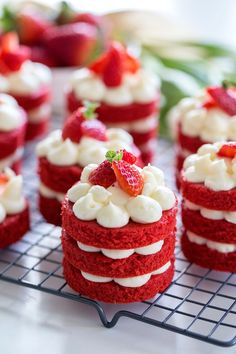 red velvet cakes with white frosting and strawberries on top, sitting on a cooling rack