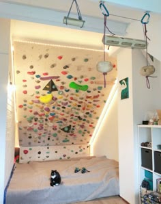 there is a climbing wall in the room that has many rocks on it and lights hanging from the ceiling