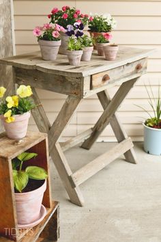 several potted plants are sitting on an old wooden table with two planters in front of it