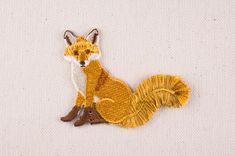 a small embroidered fox sitting on top of a white surface