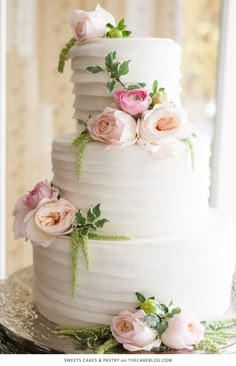 a white wedding cake with pink flowers on top