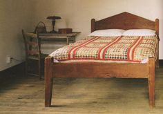 a bed sitting on top of a wooden floor next to a table with a lamp