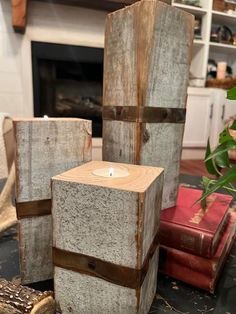 three wooden blocks with a lit candle in the middle on a table next to books