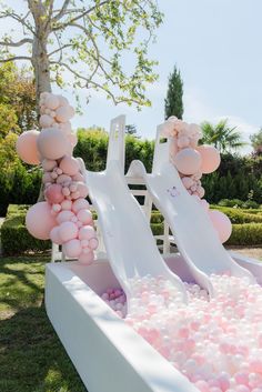 an inflatable water slide with pink and white balloons