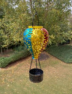 a bird feeder hanging from the side of a tree in a yard with grass and trees behind it