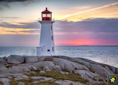 a white lighthouse sitting on top of a rocky beach next to the ocean at sunset