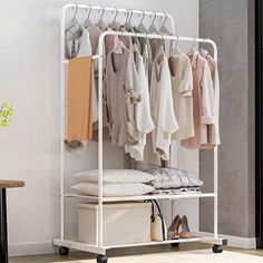 a white garment rack with clothes hanging on it and a table in front of it