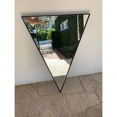 a triangle shaped mirror sitting on top of a stone floor