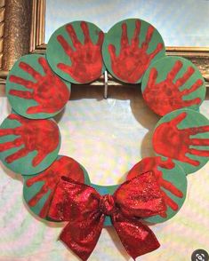 a paper plate wreath with handprints on it and a red bow hanging from the front