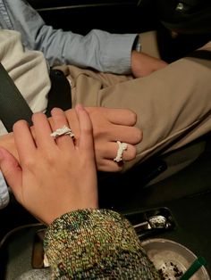 two people holding hands while sitting in a car