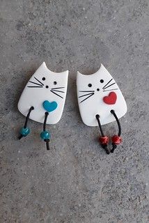 two white cats with red, blue and green hearts on their ears