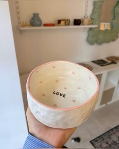 a person holding up a bowl with the word love written on it