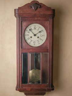 an old wooden grandfather clock hanging from the side of a wall with a pendulum on it