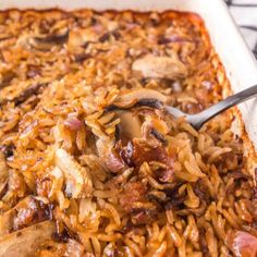 a casserole dish filled with rice, mushrooms and meat in a white pan