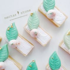 small desserts with green leaves and white frosting are arranged on top of each other