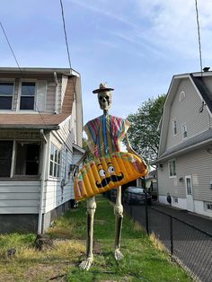 a skeleton holding a large bag in front of a house on the side of a road