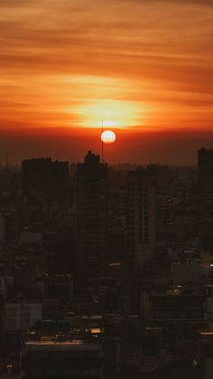 the sun is setting over a city with tall buildings and skyscrapers in the foreground