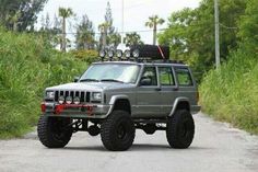 the jeep is parked on the side of the road in front of some grass and trees