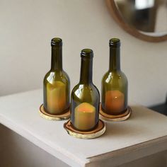 three empty wine bottles sitting on top of a wooden table next to a round mirror