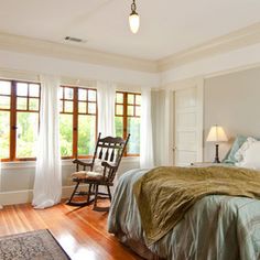 a bed sitting in a bedroom next to two windows