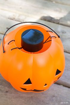 an orange pumpkin shaped speaker sitting on top of a wooden table