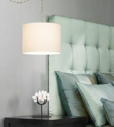 a lamp that is sitting on top of a night stand next to a bed with pillows