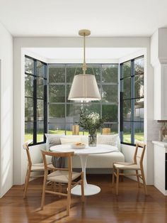 a dining room table and chairs in front of large windows