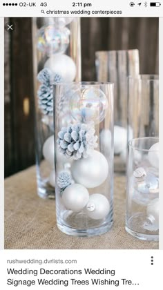 the wedding decorations are in clear vases with white balls and snowflakes on them