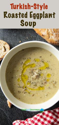 a white bowl filled with soup on top of a black table next to some bread