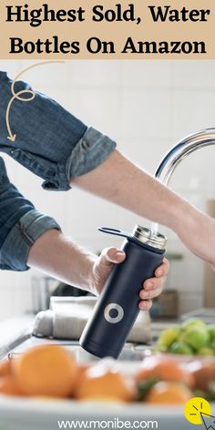 a person is holding a water bottle in front of a sink with oranges on the counter