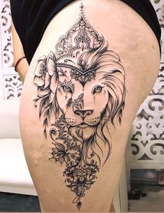 the back of a woman's thigh with a lion tattoo on it and flowers