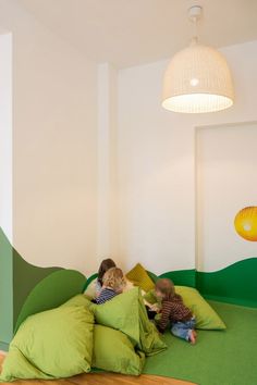 two children laying in bed with green pillows