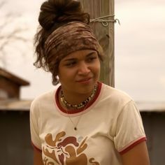 a woman standing next to a telephone pole with her hair in a topknot