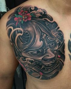 a man with a tattoo on his chest is wearing a mask and holding a flower