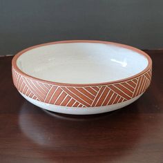 a brown and white bowl sitting on top of a wooden table