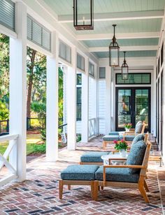 the front porch is decorated with blue and white chairs, brick pavers flooring, and hanging lanterns