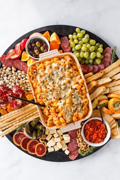 a platter filled with cheese, crackers, olives, and other snacks