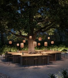 an outdoor dining area is lit up at night with paper lanterns hanging from the tree