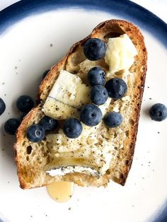 a piece of bread with blueberries and bananas on it is sitting on a plate