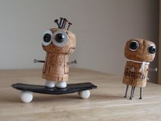 two small figurines made out of wine corks are standing on a skateboard