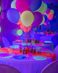 a table topped with lots of balloons next to purple and pink walls in a room