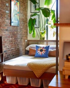 a bed sitting in the middle of a bedroom next to a brick wall with plants on it