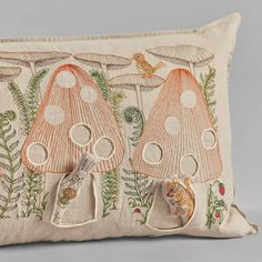 an embroidered pillow with three mushrooms on the front and one mushroom on the back,