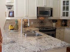 a kitchen with white cabinets and granite counter tops