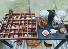 a table topped with jars filled with lots of different things next to a window sill