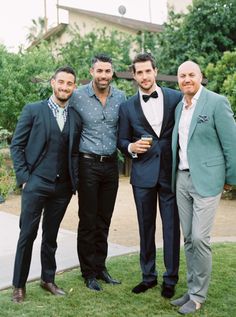 three men in tuxedos are posing for a photo with one man holding a drink