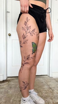 a woman with tattoos on her thigh and leg is standing in front of a door